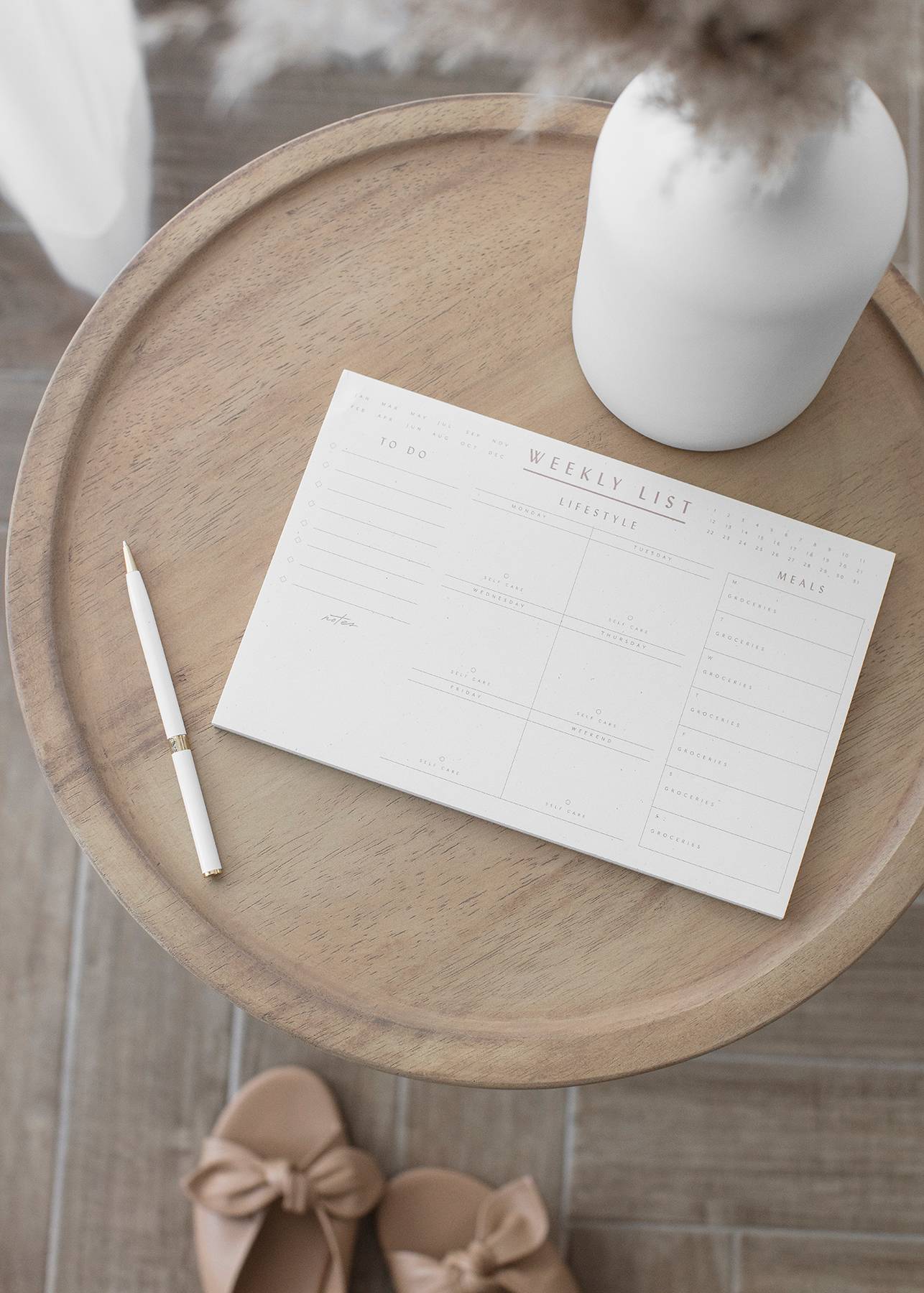 Planner on a wood tray with vase and shoes