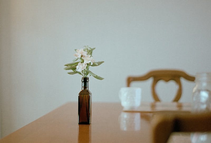 A wooden table topped with a brown bottle filled with flowers