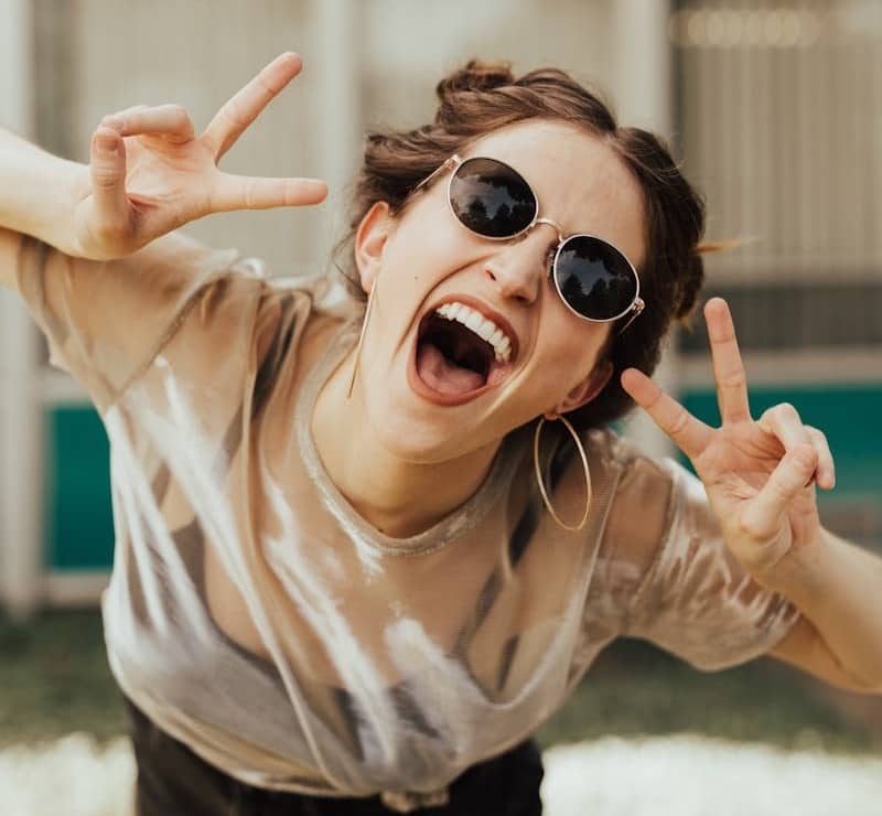 selective focus photography of jolly woman using peace hand gesture