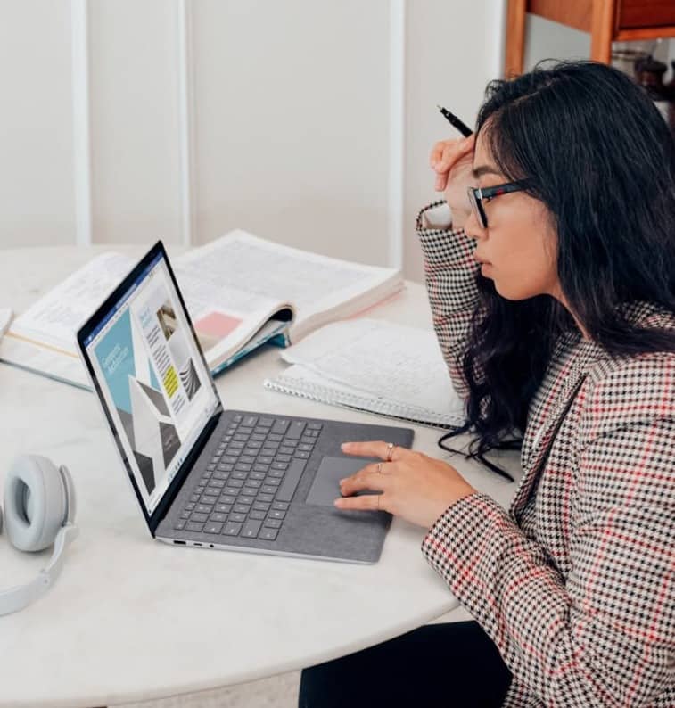 woman in red and white plaid dress shirt using microsoft surface laptop 