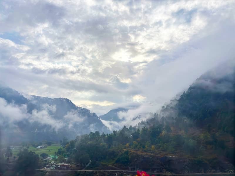 Mountains are covered with fog under a cloudy sky.