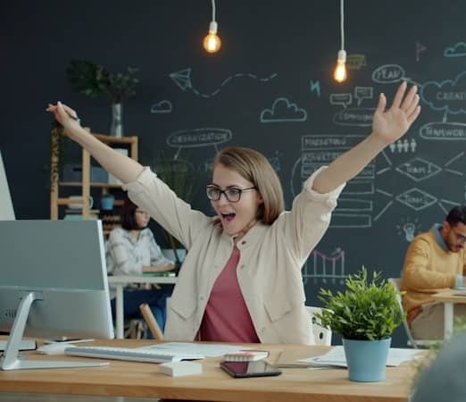 Woman celebrating success at her office desk.