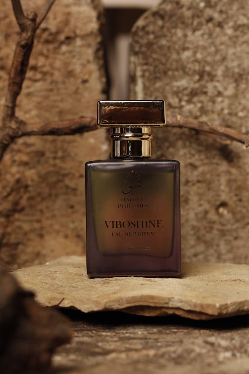Perfume bottle is resting on a stone surface.