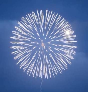 A single white firework explodes against a dark blue sky.