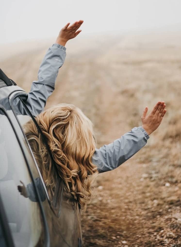 woman in gray jacket leaning on white car during daytime