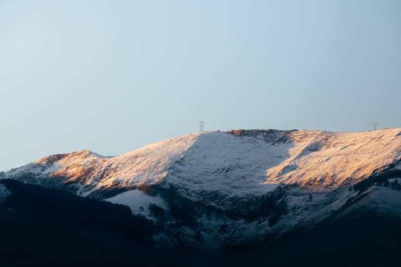 A snow covered mountain with a bird flying over it