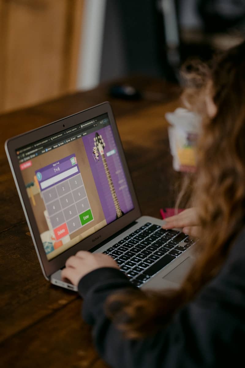 person using macbook air on brown wooden table