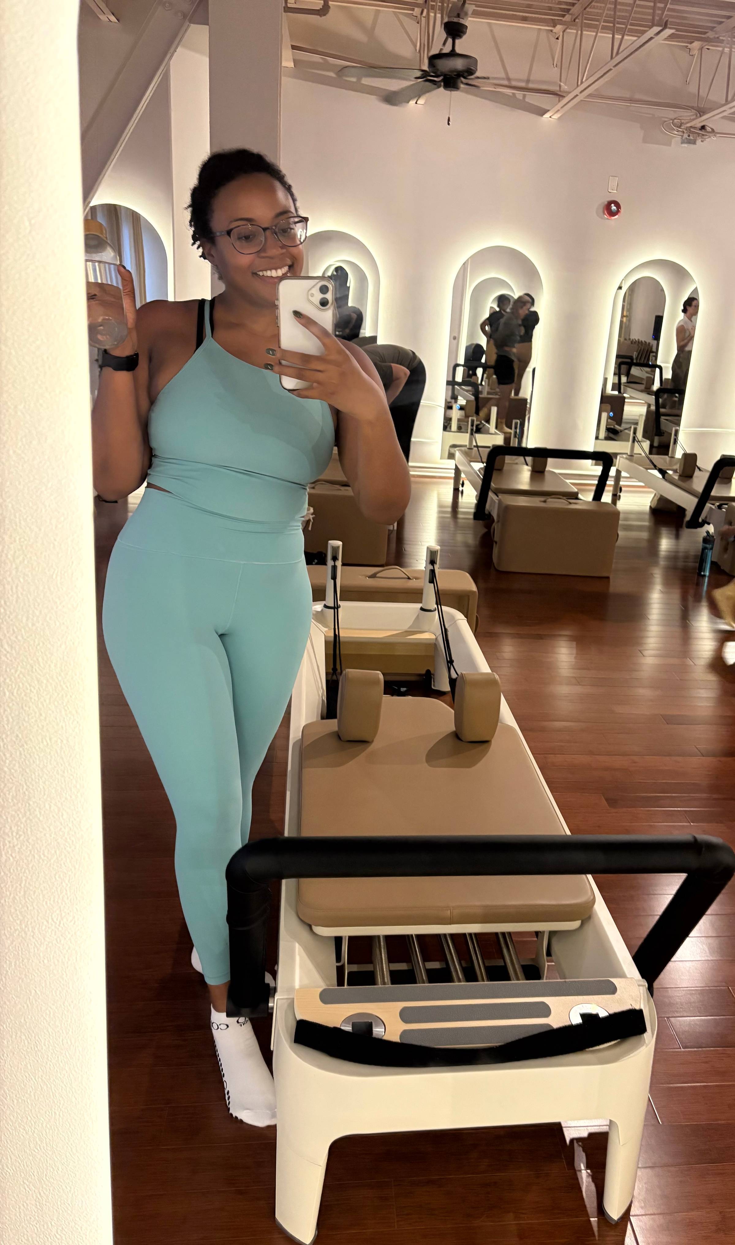 A picture of Jasmine in a blue workout set in a pilates class.
