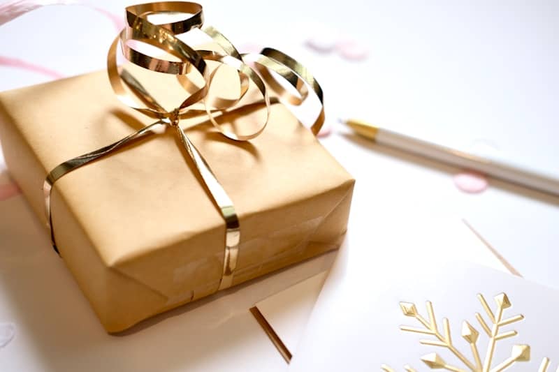 A gift wrapped in brown paper with a gold ribbon.
