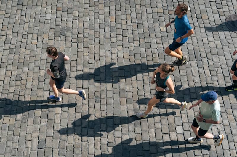 Runners race on a cobblestone street.