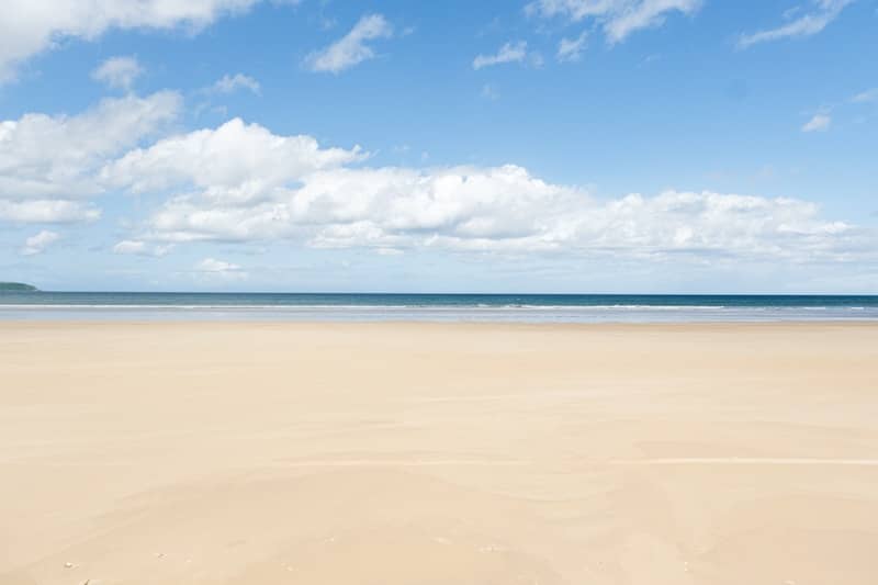 Sandy beach meets blue ocean and sky.