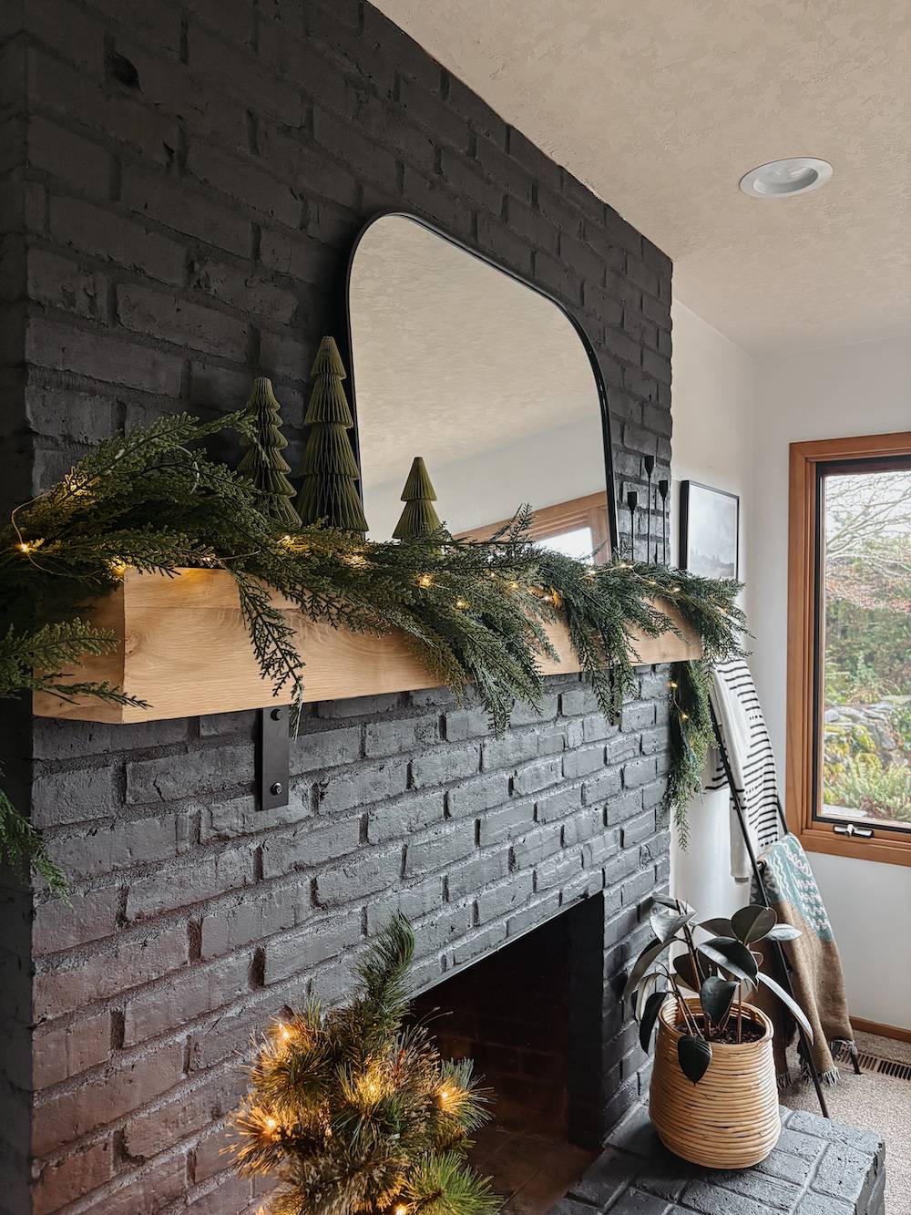 black brick fireplace with wood mantel decorated for the holidays