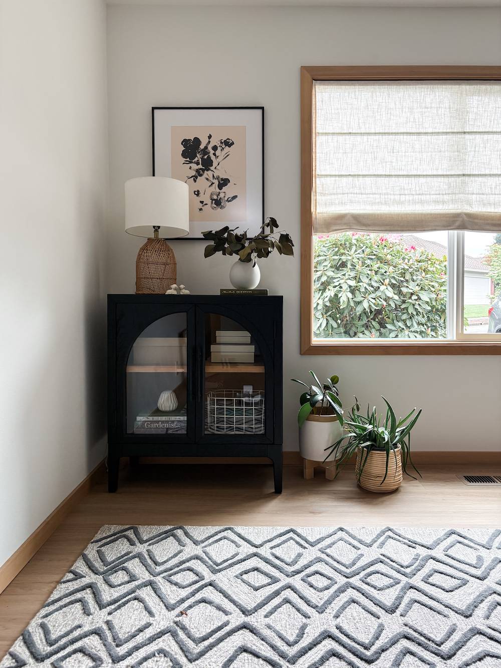 office with black cabinet, window with shades, and decor