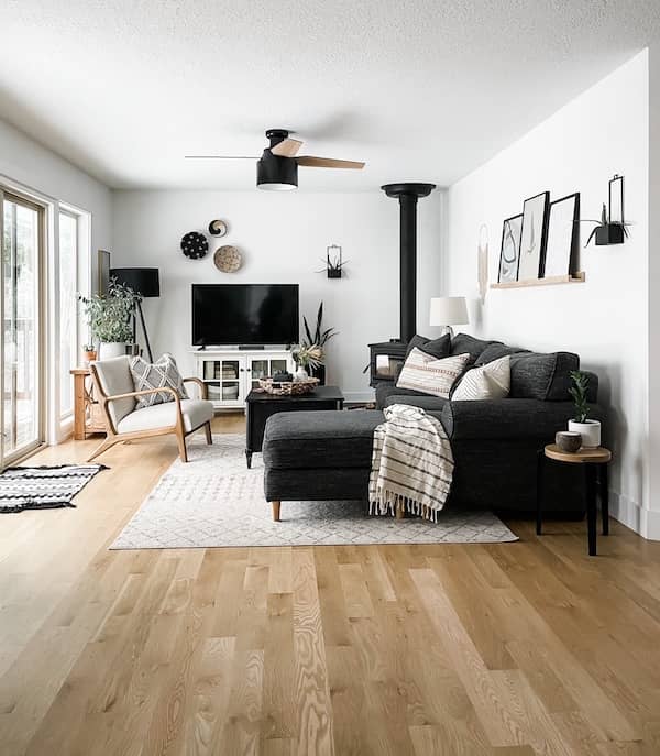 living room with black couch and light gray rug with neutral decor