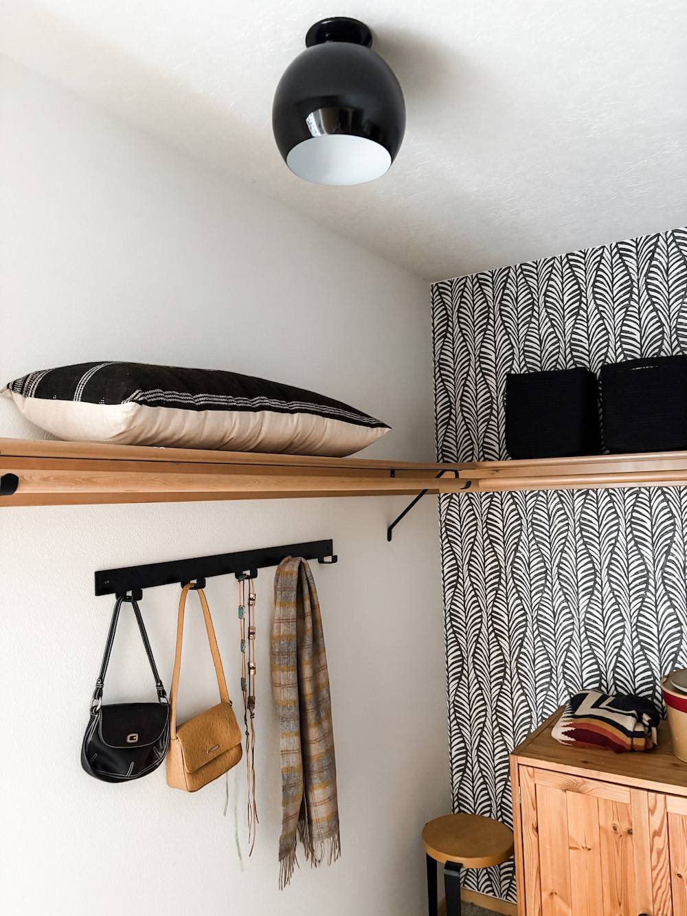 closet with wood shelf, wallpaper, and black light fixture