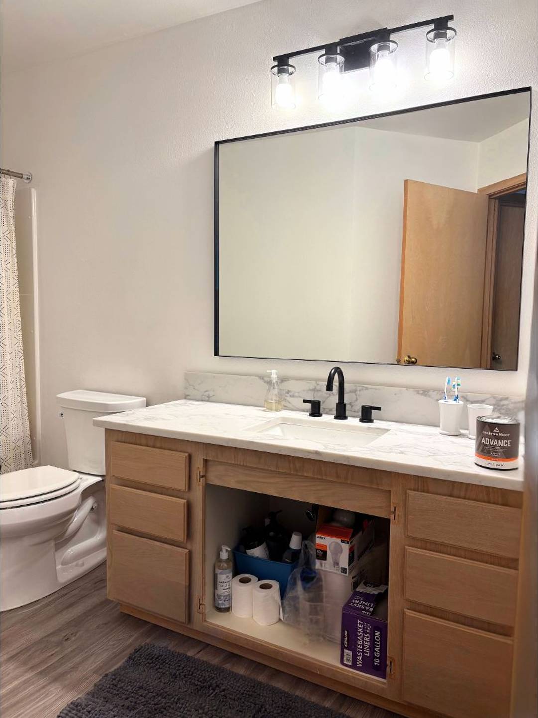 bathroom remodel with new mirror, light fixture, sink, and cabinets in process of painting