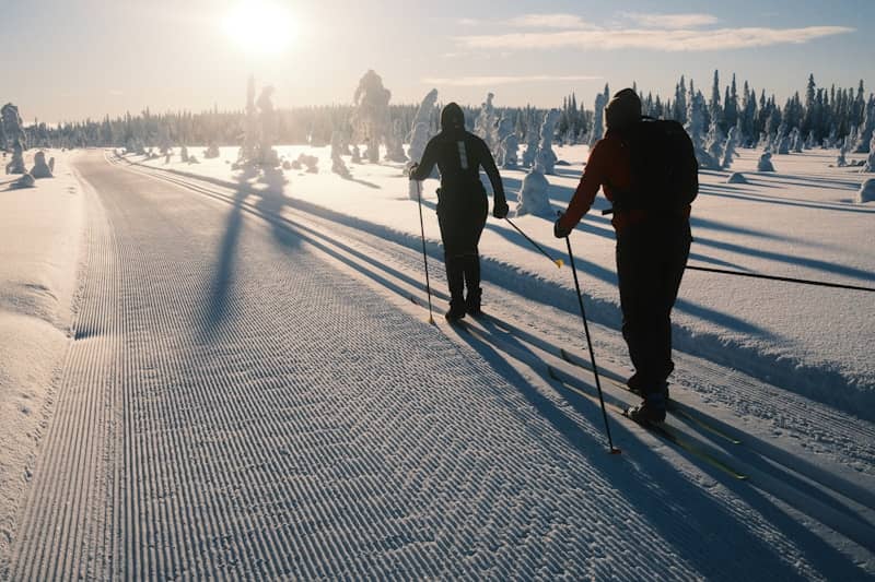 Two people cross-country skiing on a snowy trail