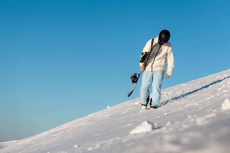 A person walking uphill with skis and poles.