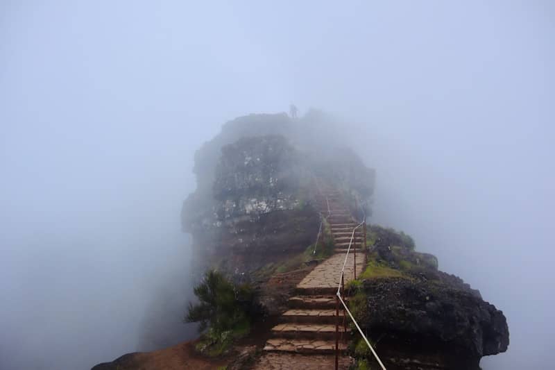 Stone steps ascend a misty rock formation