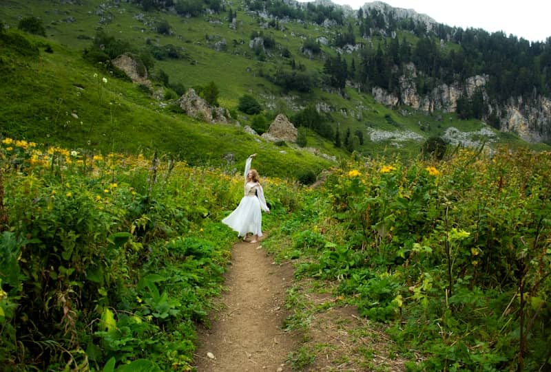 A woman in a white dress walking down a trail