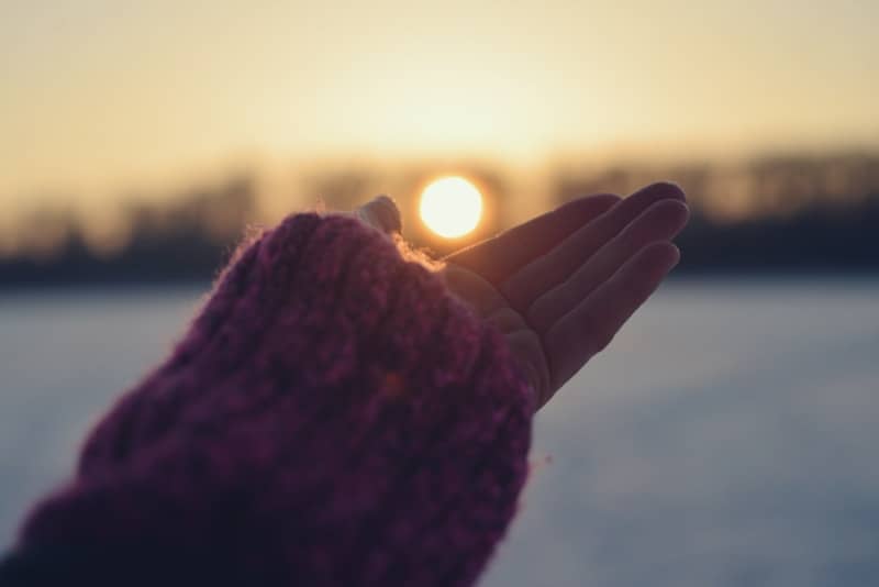 Hand reaching for the sun at sunset