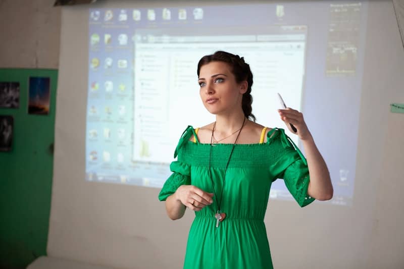 Woman in green dress presenting with projector screen projection screen.