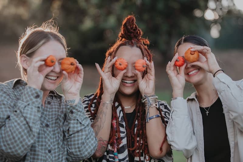 a group of women holding up pumpkins to their eyes