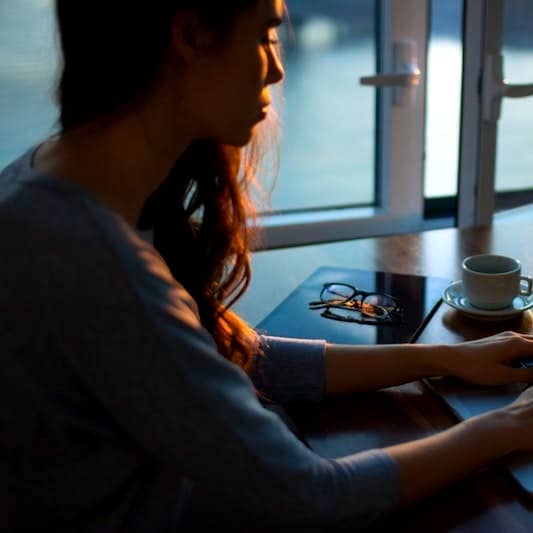 woman sitting beside table using laptop