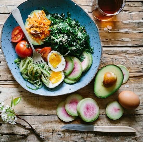 poached egg with vegetables and tomatoes on blue plate