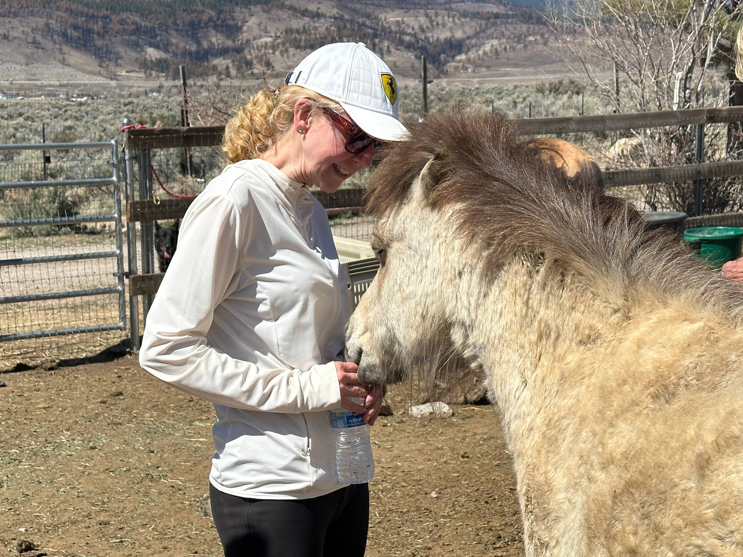 Women in white shirt and ball cap connecting face to face with Doug the Pony