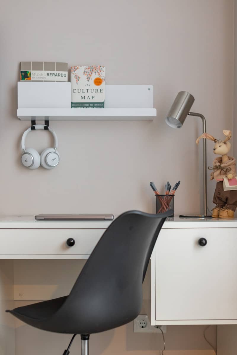 A modern desk with headphones, books, and a lamp.