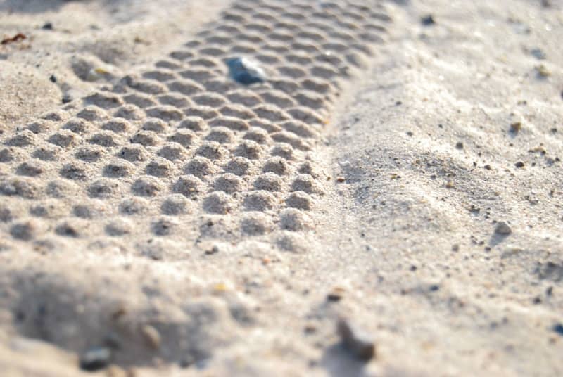 A patterned trail is embedded in the sand.