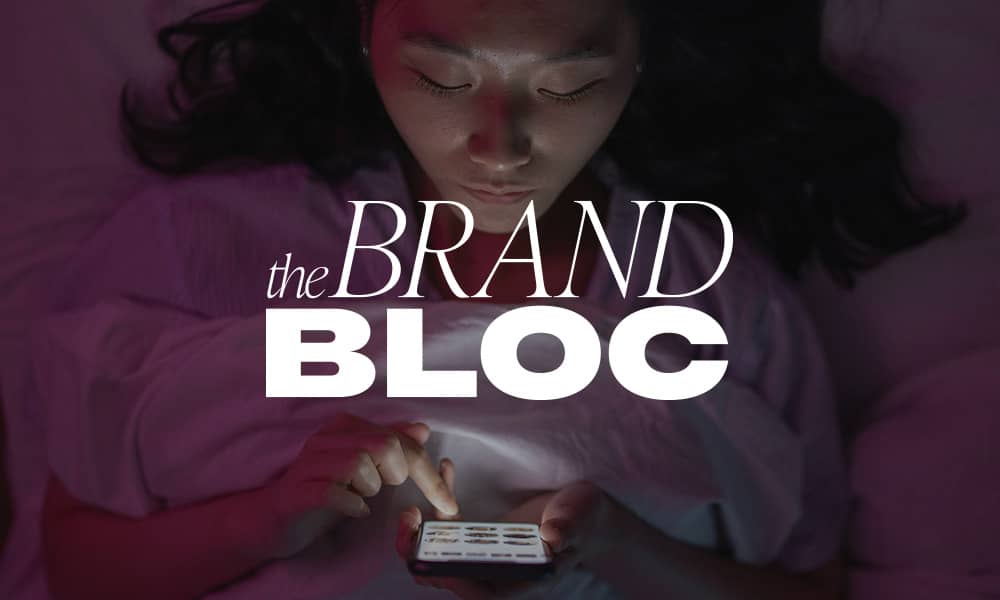Woman looking down on phone with The Brand Bloc logo