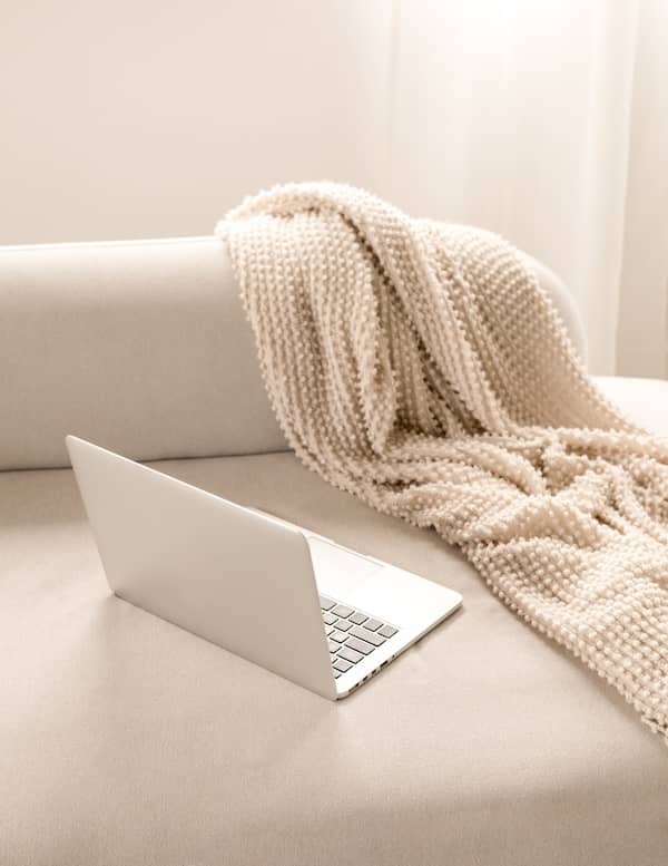 a brand strategy consultant's laptop on a couch with a throw blanket