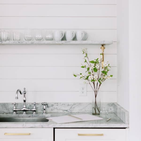 a vase of spring flowers and a notebook and pen sit on a marble kitchen counter