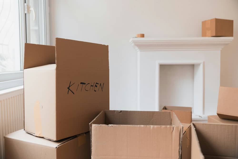 piles of open moving boxes in a bright and airy living room