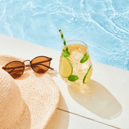 hat, glasses & drink by the pool