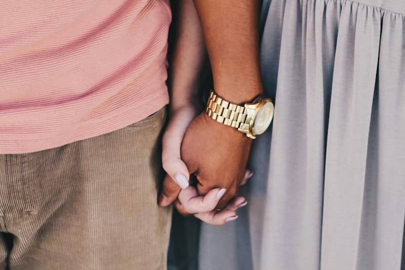 girl and boy holding hands white boy wearing gold-colored watch