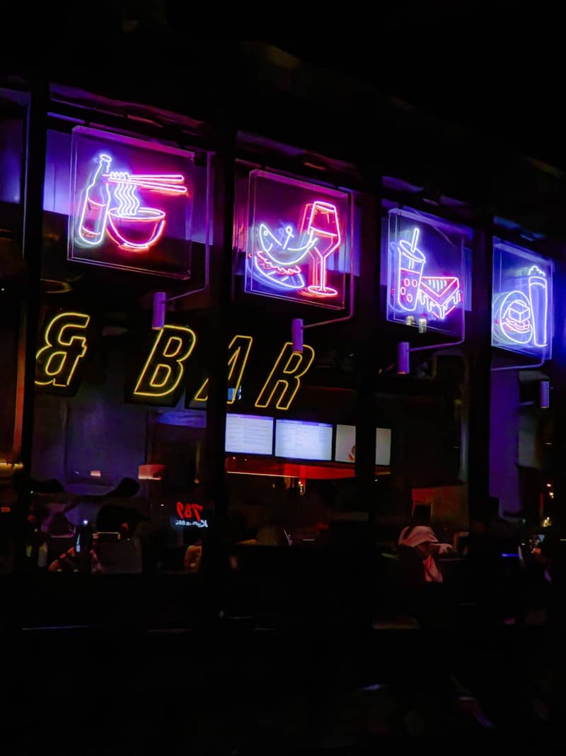 Neon signs illuminate the exterior of a bar.