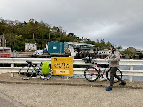 A seagull has landed on the sign and is about to eat the sandwich on Robert's bike. Robert is running to chase it off.