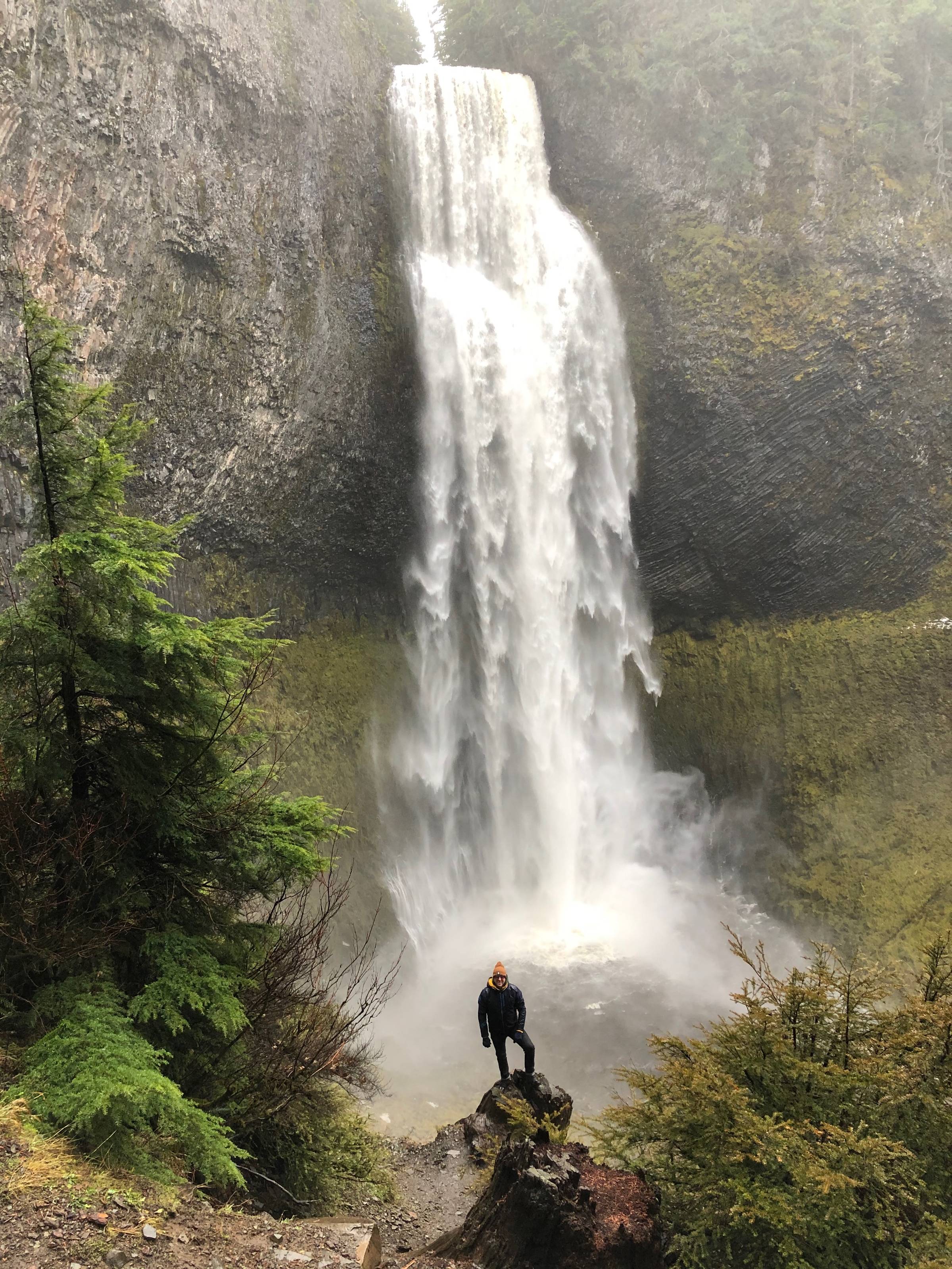 A tall waterfall against a mossy green cliff