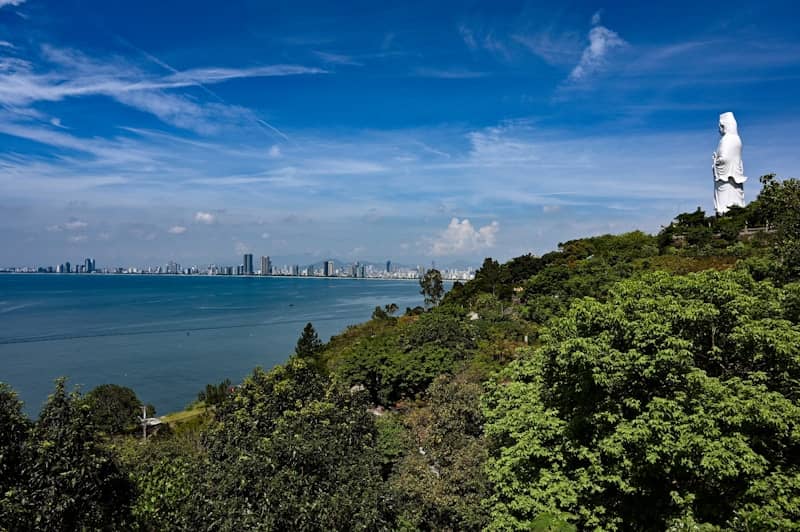 A coastal city view with a statue.