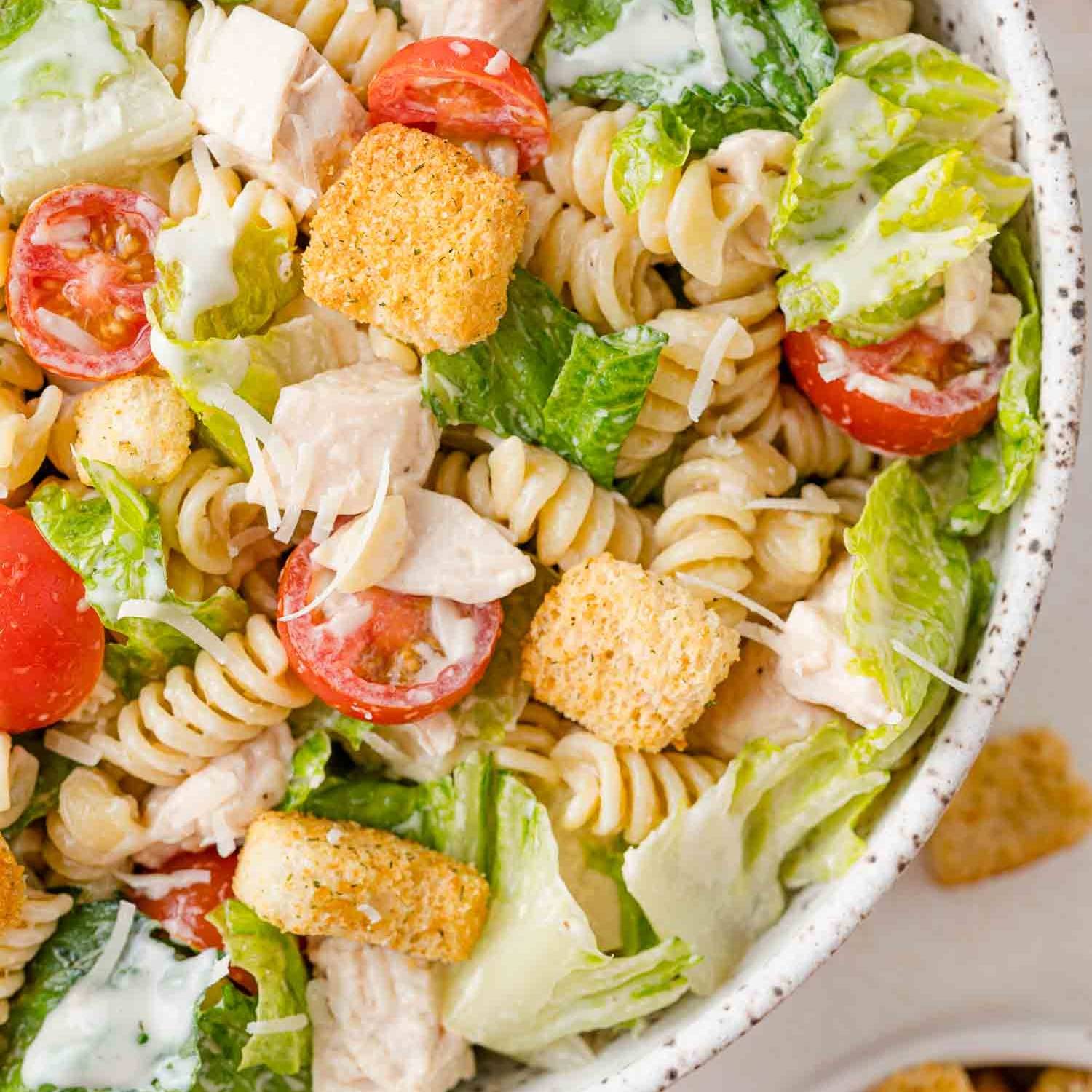 Chicken Caesar pasta salad in a speckled bowl.