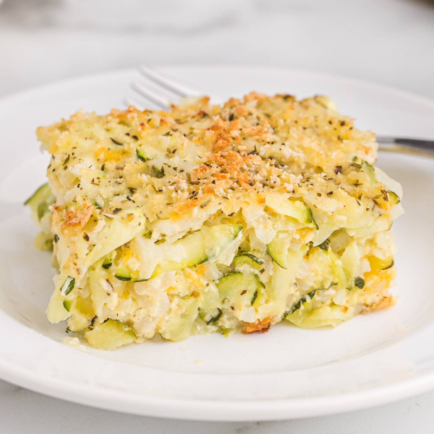 Slice of zucchini casserole on a white plate.