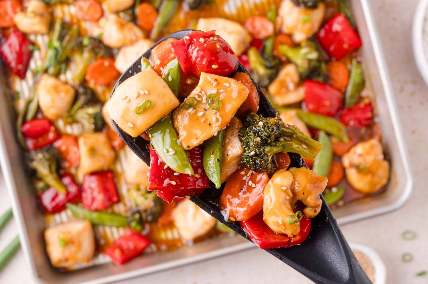 Sheet pan chicken teriyaki, with chicken, broccoli, snow peas, red bell peppers and a brownish sauce.