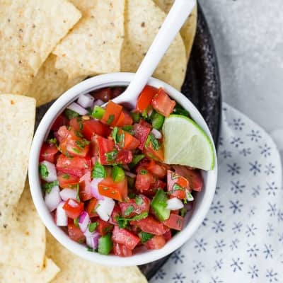 Pico de gallo in a white bowl with a white spoon.