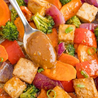 Tofu sheet pan dinner with peanut sauce being spooned on.