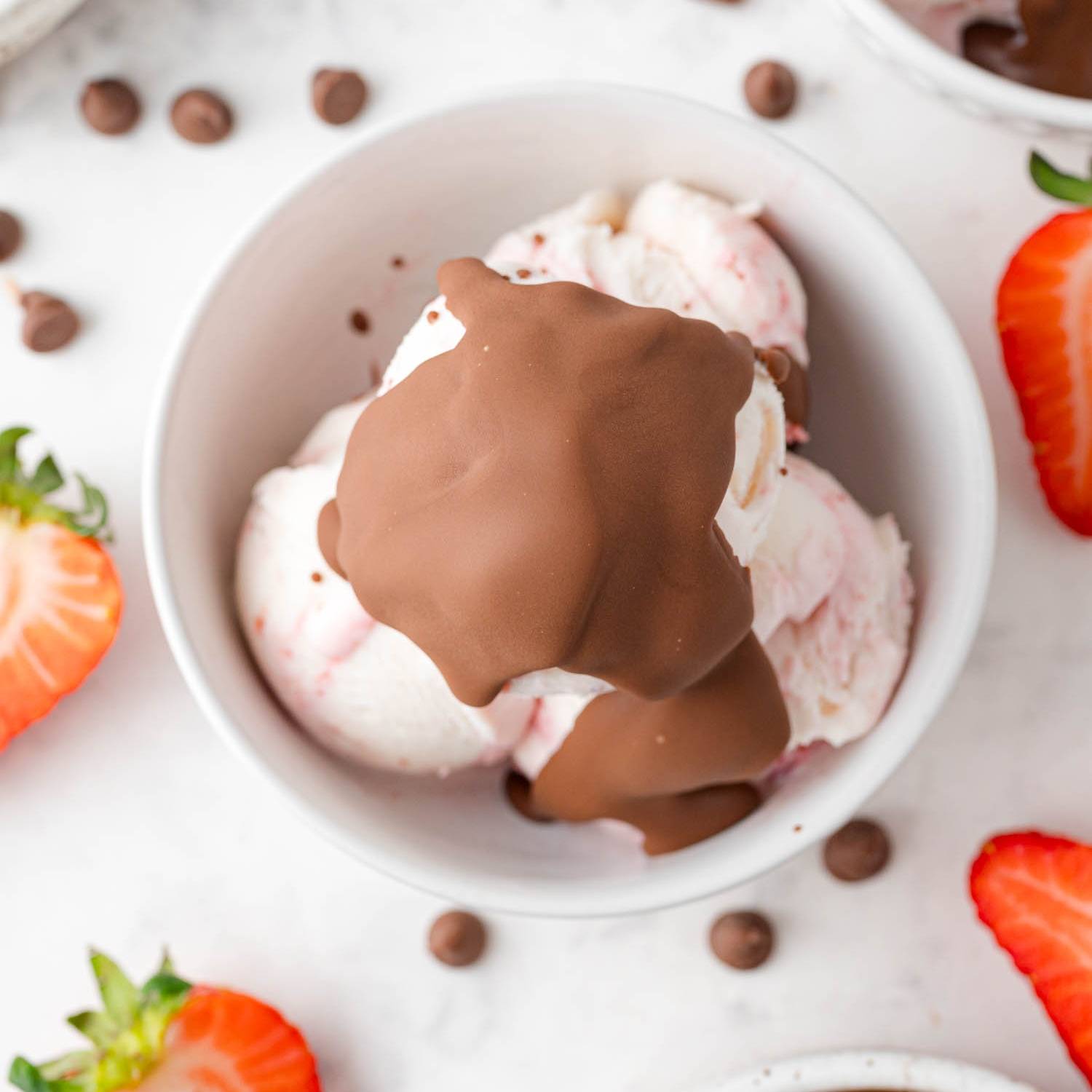 Strawberry ice cream in a bowl with chocolate shell topping.