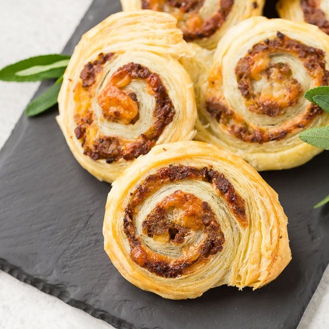 Sausage pinwheels on a black slate surface.