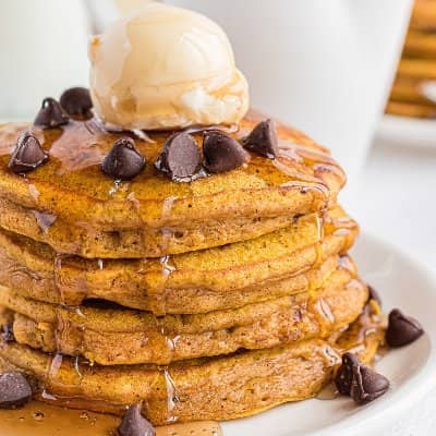 Stack of pumpkin pancakes with chocolate chips, butter, syrup.